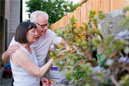A couple enjoys gardening in their backyard after installing a privacy fence from America's Backyard Fence, who also installs Vinyl Privacy Fences in Romeoville IL